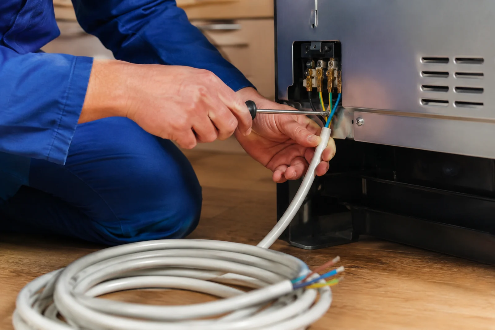 Elektryk podłączający przewód zasilający do płyty indukcyjnej lub piekarnika